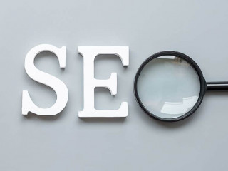 SEO (Search Engine Optimization) text and magnifying glass on gr