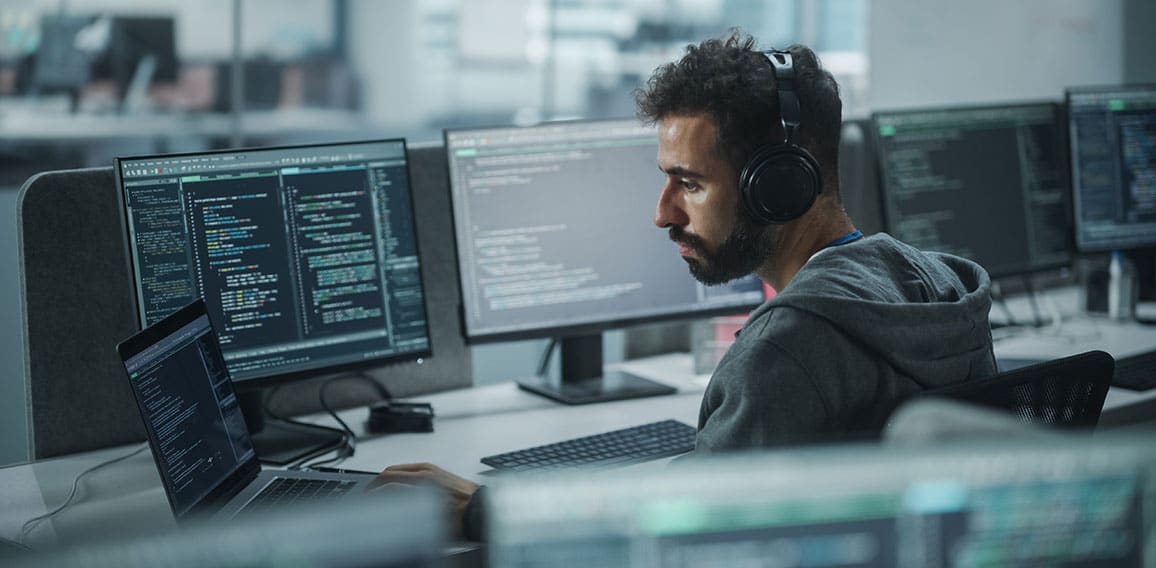 Office: Professional White IT Programmer Uses Headphones while W