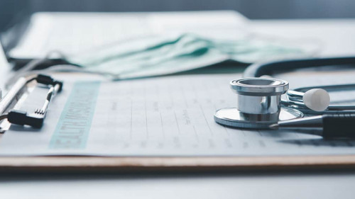 Stethoscope and calculator placed on health insurance documents,