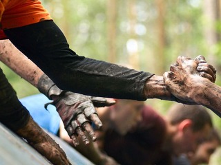 Folks help each over in a cross country with obstacle course. I