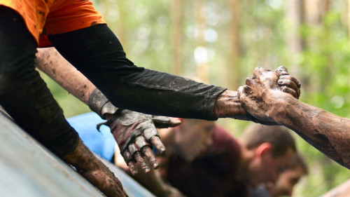 Folks help each over in a cross country with obstacle course. I