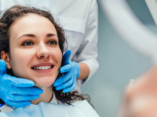 A woman is sitting at a dentist's reception. She looks in the mi