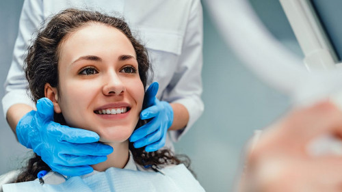 A woman is sitting at a dentist's reception. She looks in the mi