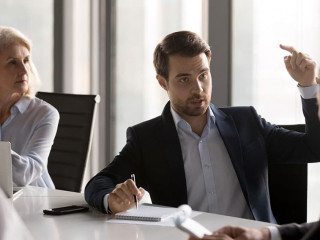 Serious businesspeople discussing new project sitting at desk in
