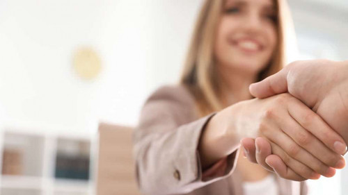 Business partners shaking hands at table after meeting, closeup.