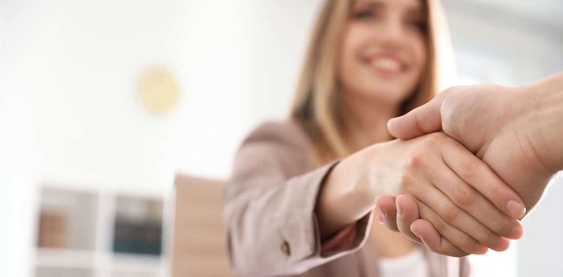 Business partners shaking hands at table after meeting, closeup.
