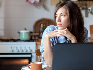 Working from home office. Upset woman using laptop and Internet. Freelancer workplace at kitchen table.