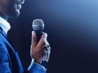Motivational speaker with microphone performing on stage, closeu