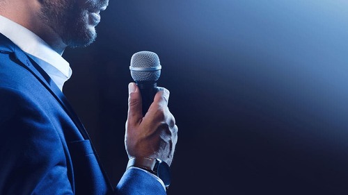 Motivational speaker with microphone performing on stage, closeu