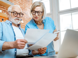 Senior couple with documents and laptop at home