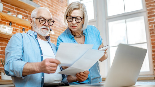 Senior couple with documents and laptop at home