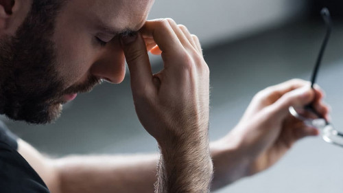 panoramic shot of depressed man with closed eyes holding glasses