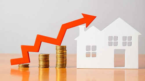 Coins on a table, a red up arrow and house. The concept of the rising price of real estate