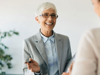 Happy mature financial consultant talks to her clients in the office.