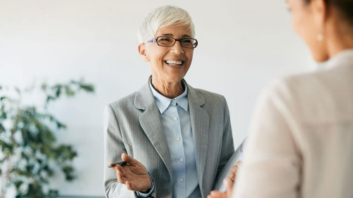 Happy mature financial consultant talks to her clients in the office.
