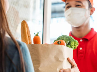 Asian deliver man wearing face mask in red uniform handling bag