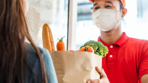 Asian deliver man wearing face mask in red uniform handling bag