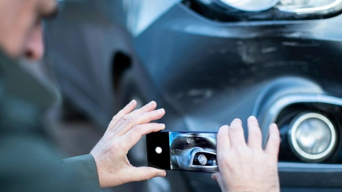 Male Driver Taking Photo Of Damaged Car After Accident For Insur