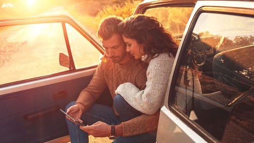 Beautiful couple on road trip, they are taking a break from driv