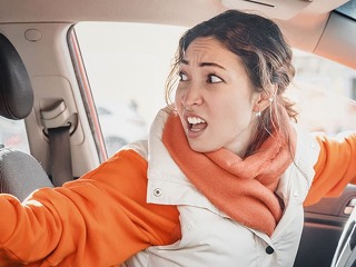 The annoyed female driver was backing up and accidentally hit a parked car. Accident and insurance