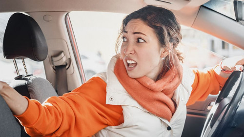 The annoyed female driver was backing up and accidentally hit a parked car. Accident and insurance