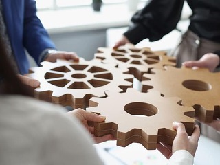 Efficient business team connects wooden gears into one