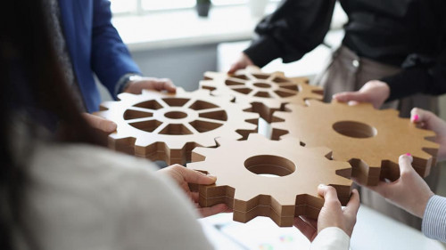 Efficient business team connects wooden gears into one