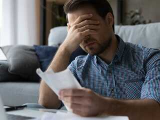 Frustrated desperate millennial man checking bills for payments