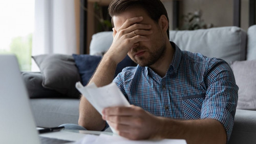 Frustrated desperate millennial man checking bills for payments