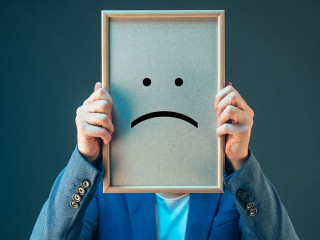 Businesswoman is pessimistic, holding smiley emoticon over face