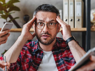 Overworked businessman sitting at laptop overloaded with work multiple tasks in modern office