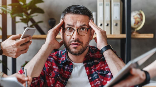 Overworked businessman sitting at laptop overloaded with work multiple tasks in modern office