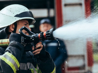 selective focus of firefighter with water hose extinguishing fir