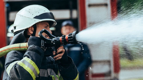 selective focus of firefighter with water hose extinguishing fir