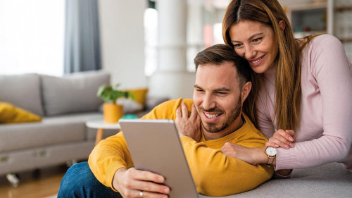 Couple in love using tablet computer at home and having fun