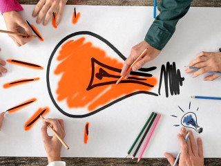 Six people, men and women, drawing bright yellow light bulb on a