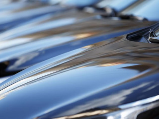 The hood of the car. Row of cars on a parking lot. Black sedan c