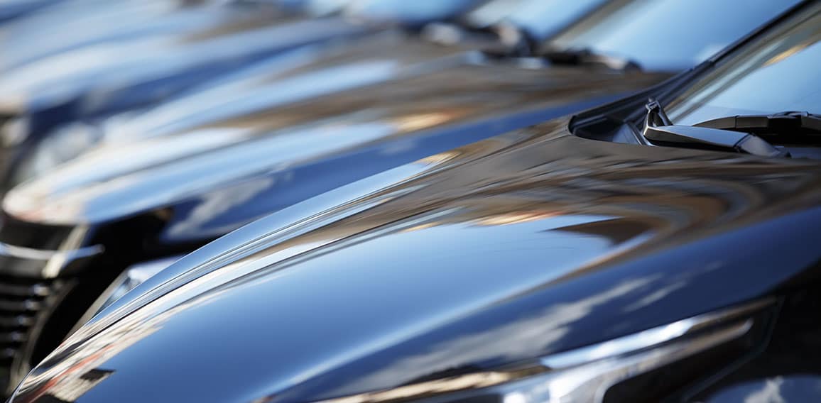 The hood of the car. Row of cars on a parking lot. Black sedan c