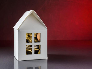 House model with Euro coins over red background with copy space