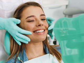 European young woman smiling while looking at mirror in dental c