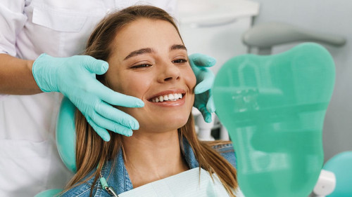 European young woman smiling while looking at mirror in dental c