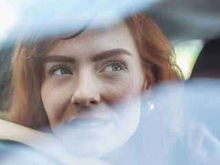 Young Woman Embracing Her New Car. Excited young woman and her new car indoors. Young and cheerful woman enjoying new car hugging steering wheel sitting inside