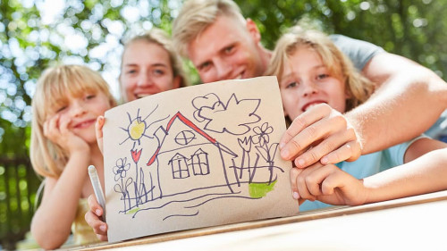 Familie zeigt bunte Zeichnung mit Eigenheim