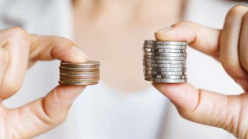 Hands compare two piles of coins of different sizes.