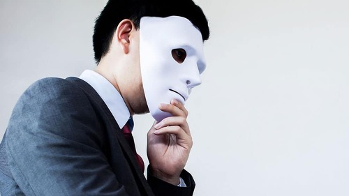 Business man giving dishonest handshake hiding in the mask - Business fraud and hypocrite agreement