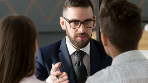 Rear view couple meets with realtor or real estate agent