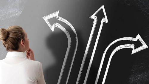 decision making concept with rear view of woman looking at chalkboard with arrows pointing in different directions