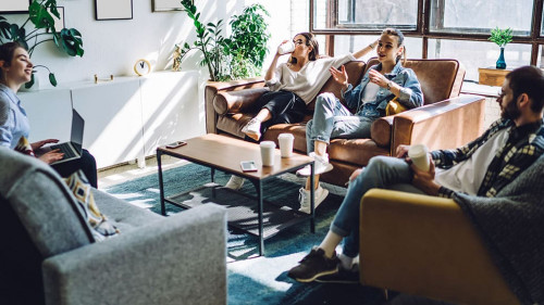 Relaxed friends resting and using laptop at home