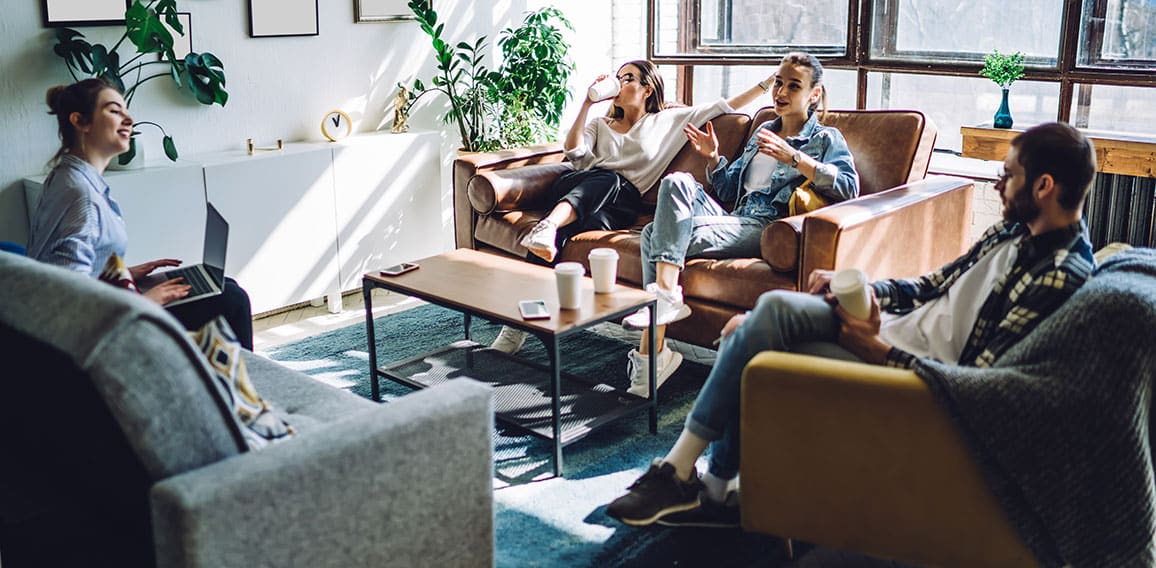 Relaxed friends resting and using laptop at home