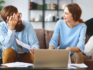 married couple with bills receipts documents and laptop at home